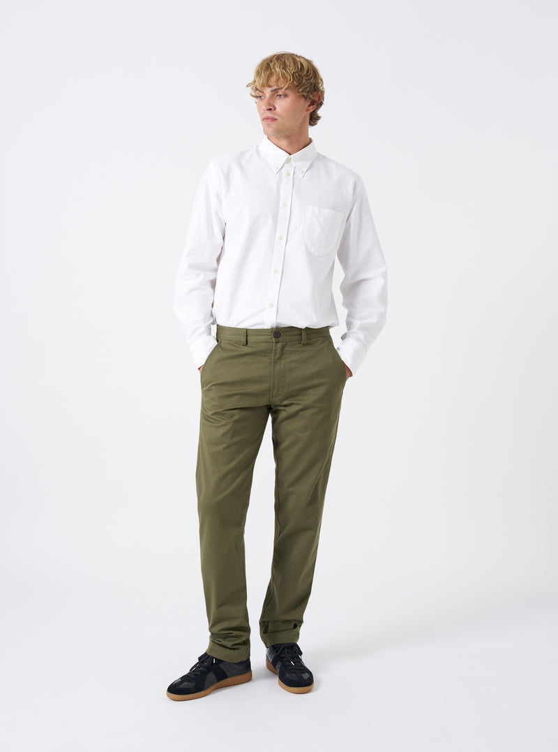 Front full-length view of a model wearing the Light Olive Twill Military Chino on a white backdrop. The model is styled wearing the olive green trousers, displaying the mid-rise waist, front slant pockets, and tapered leg cut.