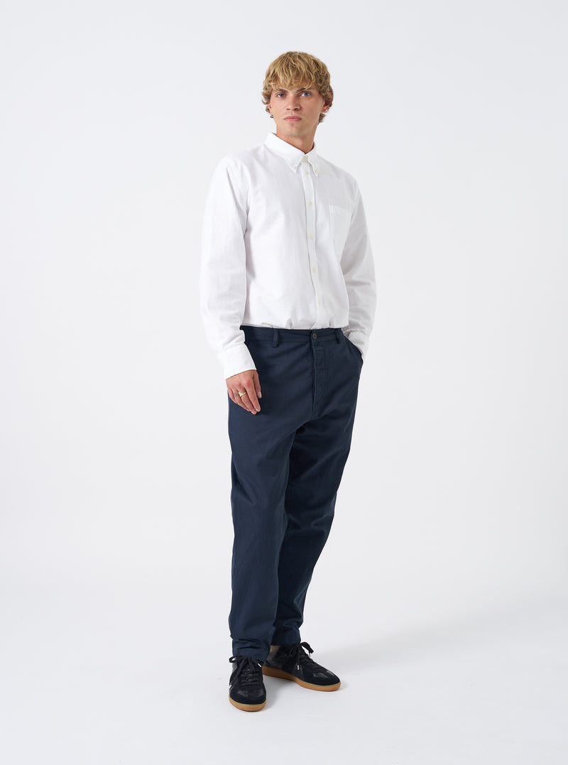 Front view of a model wearing the Navy Twill Military Chino set against a plain white background. The model stands wearing the dark navy trousers, showing the mid-rise fit, side slant pockets, and structured tapered leg silhouette.