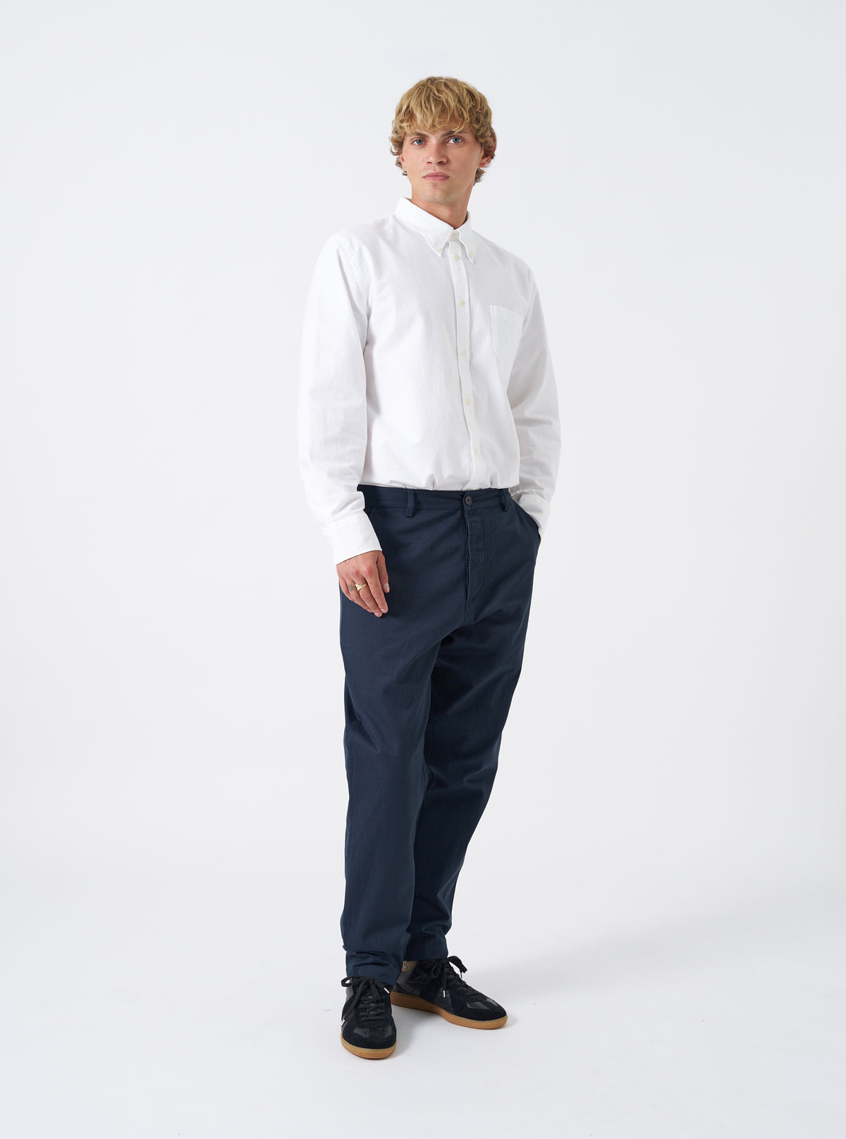 Front view of a model wearing the Navy Twill Military Chino set against a plain white background. The model stands wearing the dark navy trousers, showing the mid-rise fit, side slant pockets, and structured tapered leg silhouette.