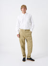 Full-length front view of a model wearing the Sand Twill Military Chino against a plain white background. The model stands wearing the sand trousers paired with footwear, highlighting the mid-rise fit and clean tapered leg silhouette.