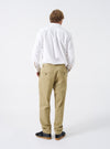 Rear view of a model wearing the Sand Twill Military Chino set against a simple white studio backdrop. The model is shown from behind, demonstrating the fit across the hips, rear buttoned pockets, and relaxed tapered cut through the legs.