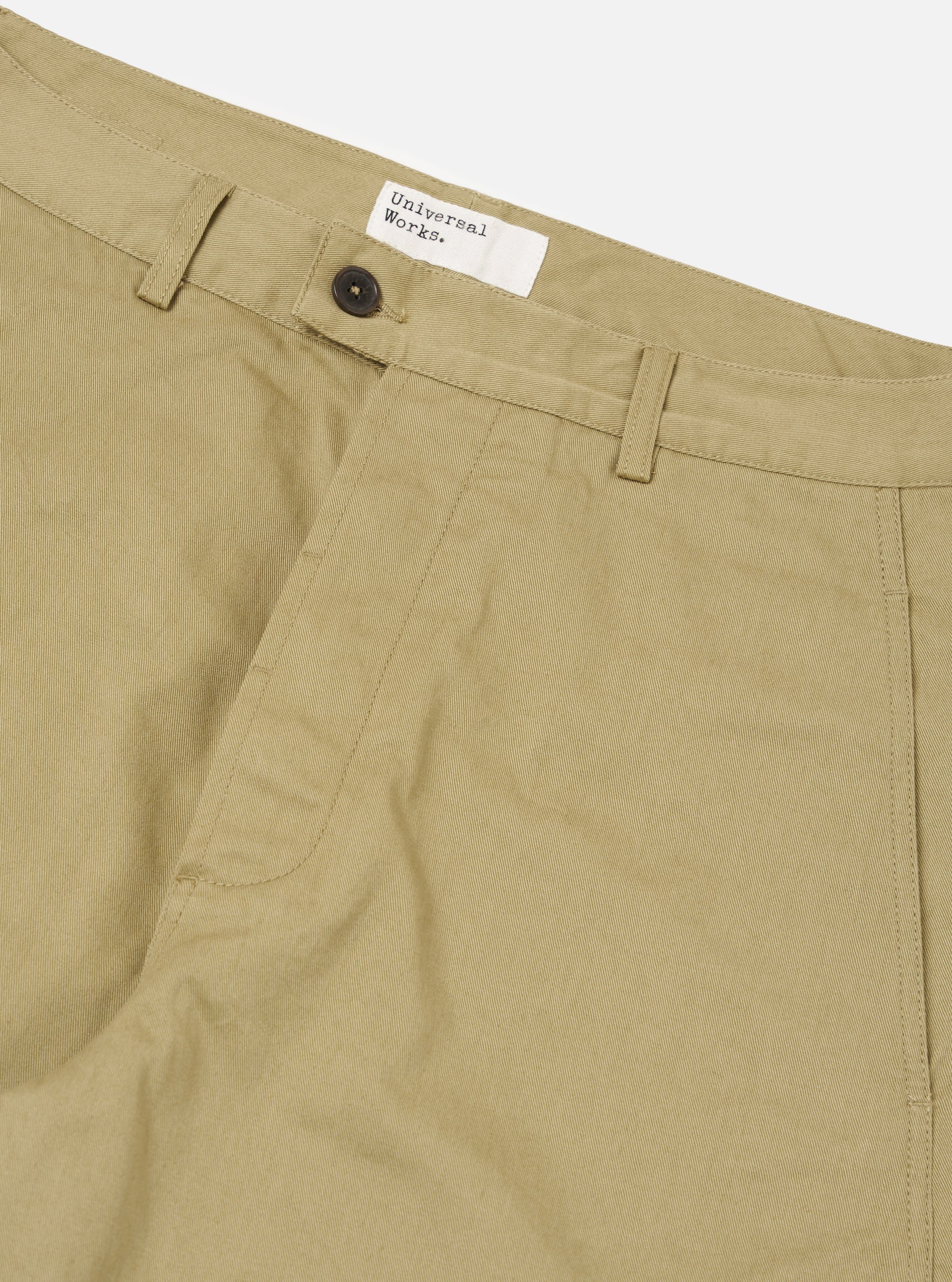 Close-up of the Sand Twill Curved Pant, showcasing the sand-colored twill fabric, curved design, button closure, and brand tag on a clean, white background.