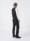 Rear perspective of a model wearing the Black Twill Aston Pant on a clean off-white backdrop. The model is shown standing in the slim black trousers, emphasizing the tailored fit through the legs and rear pocketing.