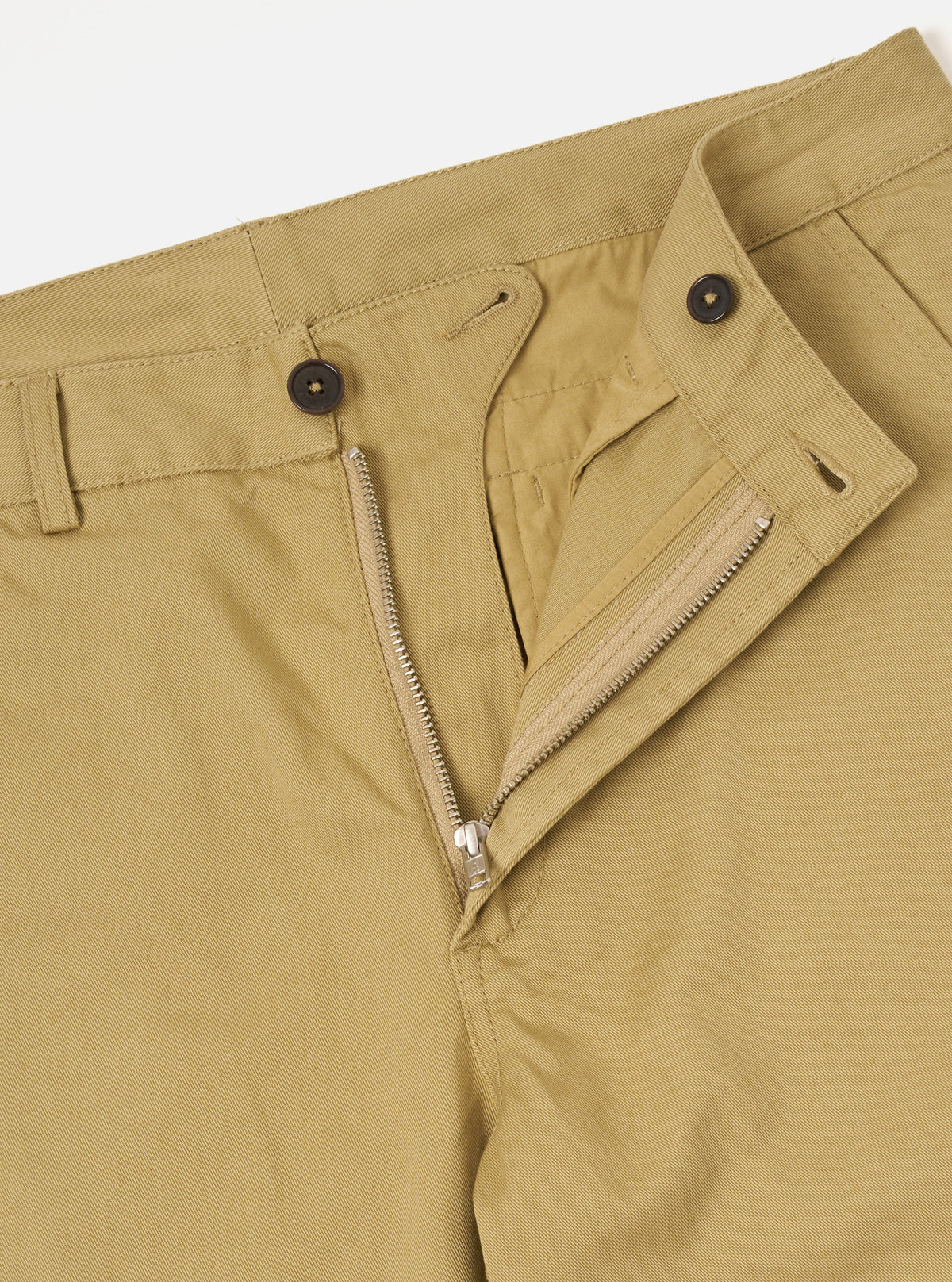 Close-up rear detail shot of the Sand Twill Aston Pant set against a clean white backdrop. Highlights the rear flap pockets with button fastenings, clean tailored seams, and fine sand-colored 3/1 cotton twill weave fabric.