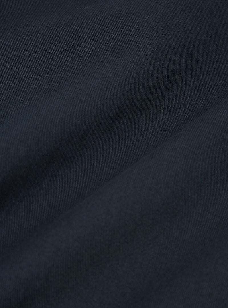 Close-up of the Navy Twill Military Chino fabric. The dark blue twill weave is clearly visible, showing the texture and quality of the material.