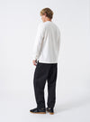 Rear view of a male model wearing the Black Twill Fatigue Pant set against a plain studio backdrop. Shows the fit across the seat, rear buttoned patch pockets, waist adjustment tabs, and straight-leg drop in black cotton twill.