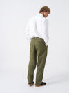 Alternate view of a model wearing the Light Olive Twill Double Pleat Pant against a plain backdrop. Highlights how the trouser drapes on the body, emphasizing the loose fit, waist pleats, and light olive twill texture.
