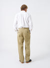 Side perspective of a model wearing the Sand Twill Double Pleat Pant against a neutral background. Demonstrates the relaxed fit, draped twill fabric, side pocket entry, and full leg cut.
