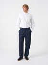 Front view of a model wearing the Navy Twill Double Pleat Pant on a plain backdrop. The trousers feature a roomy wide fit and double pleats, styled with smart footwear to show overall length and drape.