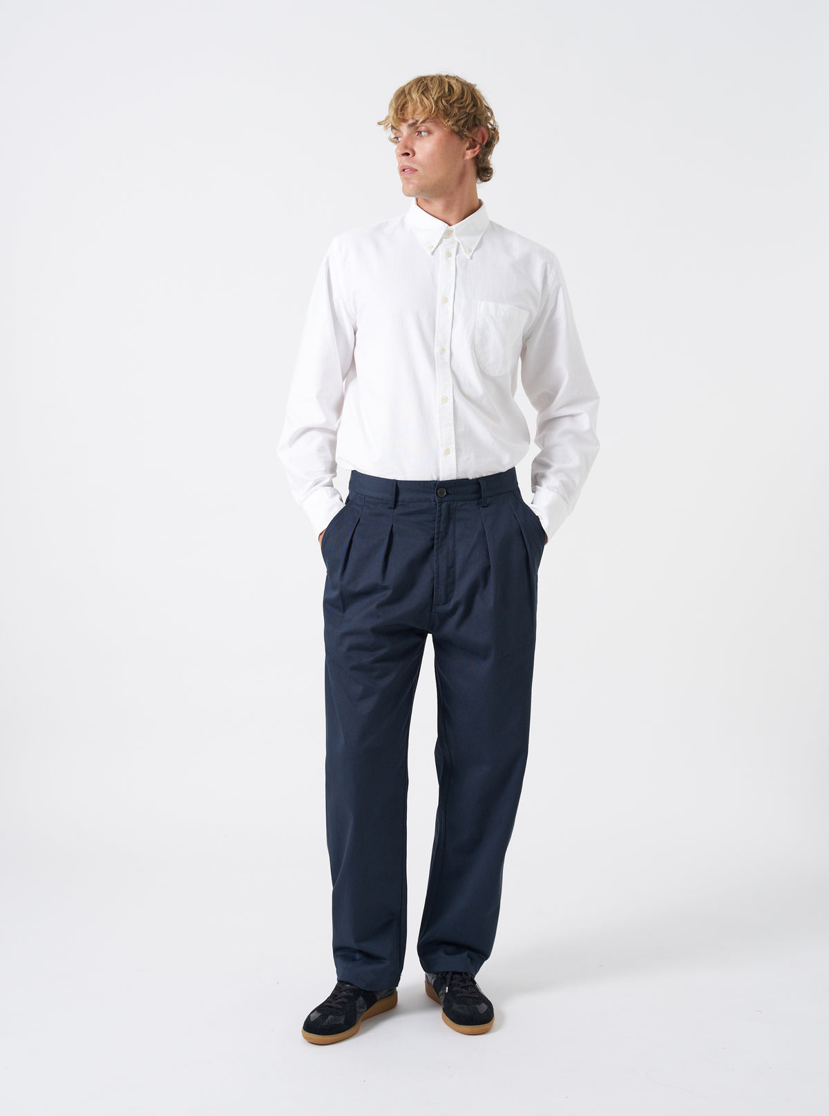 Front view of a model wearing the Navy Twill Double Pleat Pant on a plain backdrop. The trousers feature a roomy wide fit and double pleats, styled with smart footwear to show overall length and drape.