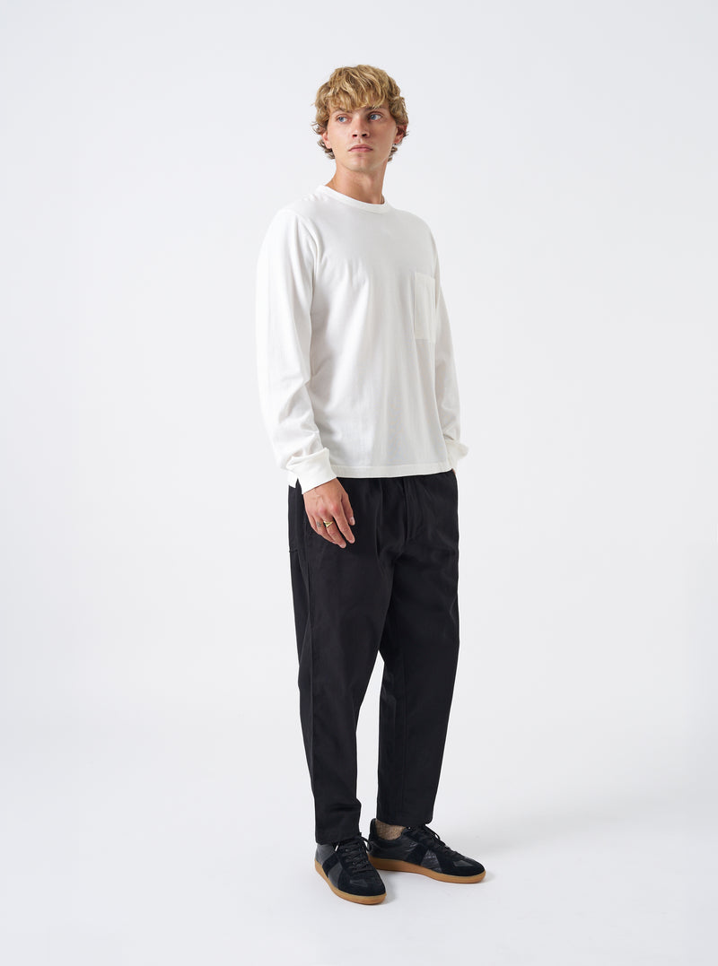 A model wears the Black Twill Hi Water Trouser against a white background. The front view highlights the elasticated drawstring waist, relaxed fit around the hips, tapered leg silhouette, and cropped ankle length.