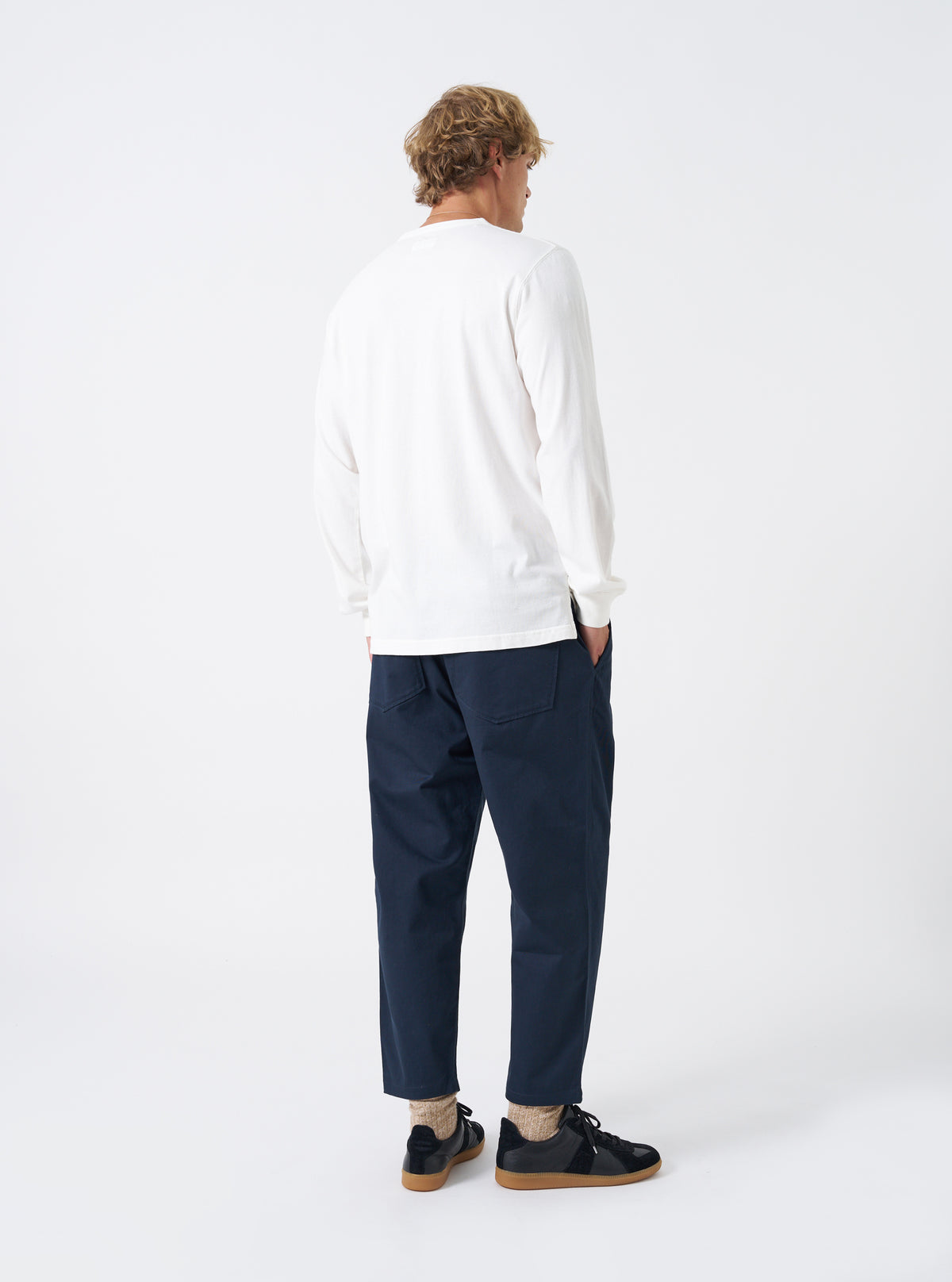 Rear shot of a model wearing the Navy Twill Hi Water Trouser against a plain white background. Shows the rear patch pockets, comfortable gathered waistband, straight loose thigh, and cropped hem length above the shoes.