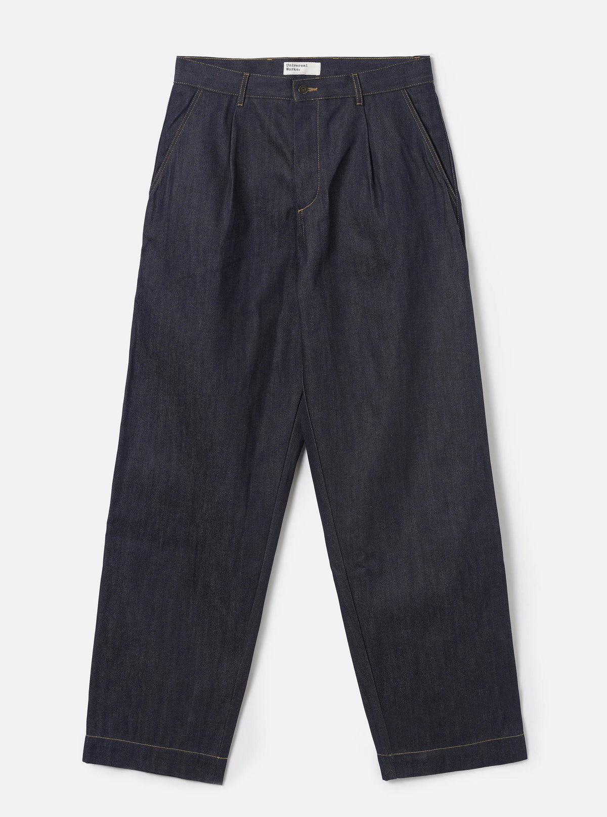 Full-length front shot of a male model wearing the Indigo 13oz Selvedge Denim Duke Pant - Longer Length against a plain off-white background. The image displays the loose, wide fit, double pleats, dark blue denim, and turned-up hems.