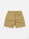 The Sand Twill Beach Short is presented as a flat lay from the rear against a plain white background. The shorts are a light sand color and feature a visible elasticated waistband and a single square patch pocket on the right side. The cotton twill fabric has a fine diagonal weave.
