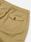 The Sand Twill Beach Short is displayed as a flat lay against a plain white background, showing the back of the garment. The shorts feature an elasticated waistband and a single patch pocket on the right rear side. The cotton twill fabric is a light sand color with a visible diagonal weave.
