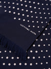 Close-up of a Navy Dot Print Short Scarf with fringe. The scarf is navy with white dots and the words "universal works." are printed on it.