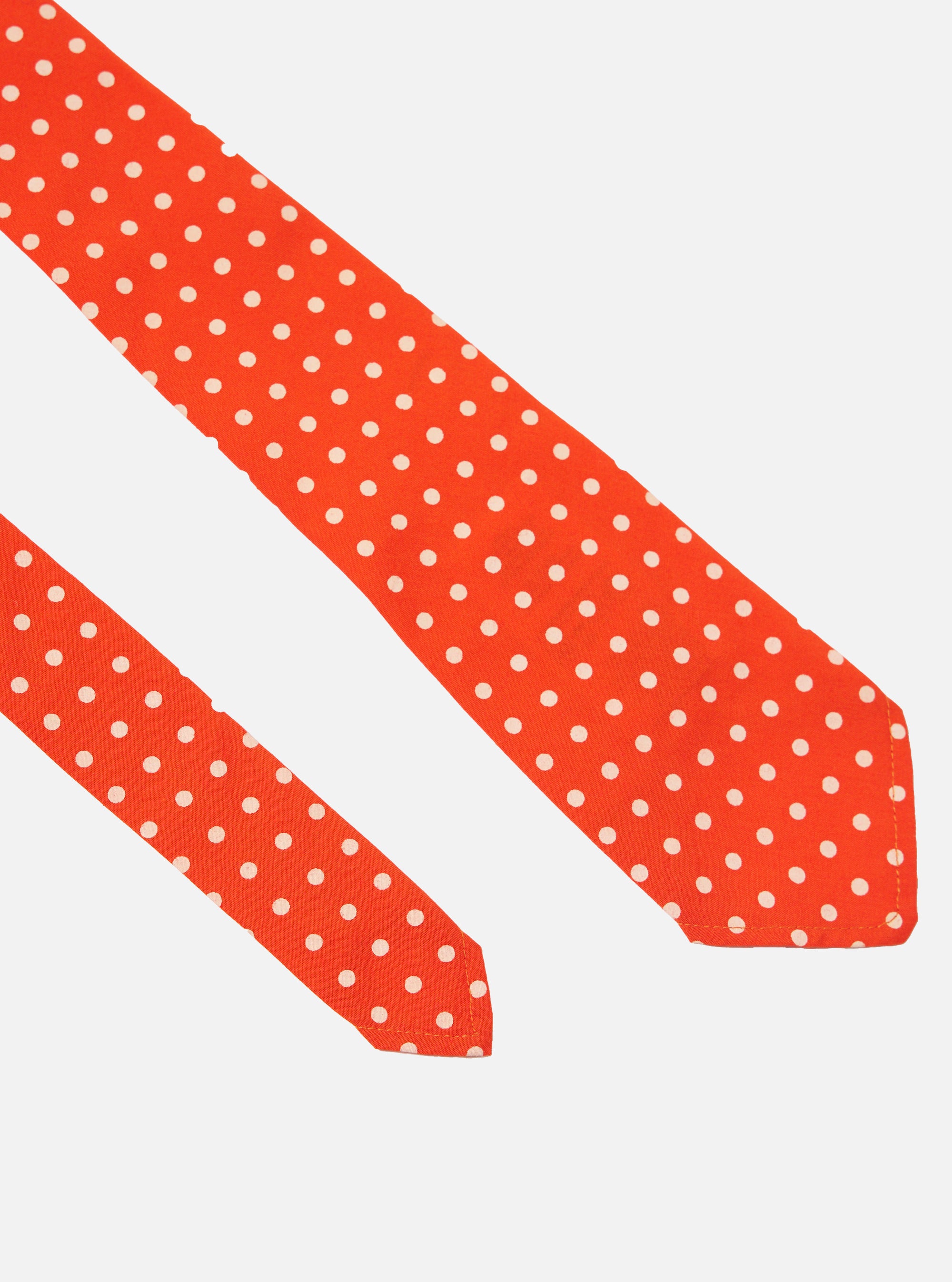 Close-up of an Orange Dot Print Tie on a white background. The tie is orange with white polka dots. The image is well-lit and the tie is in focus.