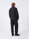 Rear view of a model wearing the Black Twill MW Fatigue Jacket against a plain neutral background. The photograph highlights the straight hemline, soft shoulder drape, structured twill fabric, and overall fit from behind.