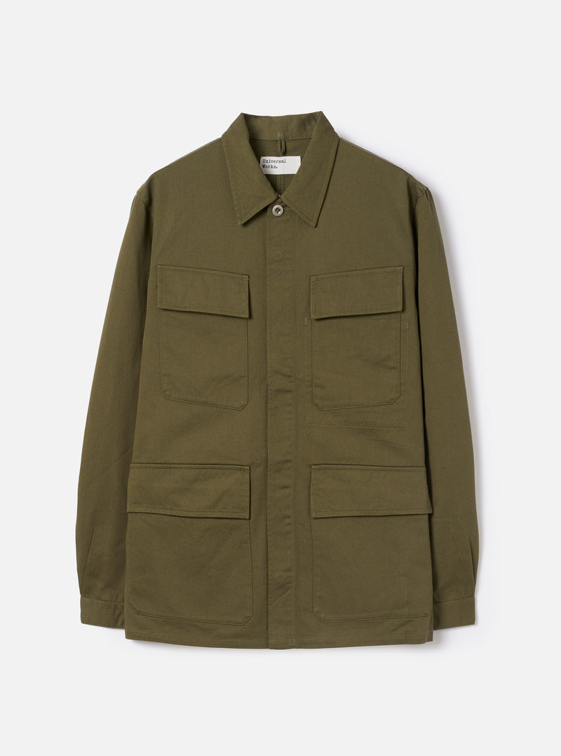 Front view of the Light Olive Twill MW Fatigue Jacket set against a plain white background. The military-inspired jacket displays four front patch pockets with flaps, a pointed collar, and a concealed front button closure.