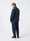 A model displays the Navy Twill MW Fatigue Jacket from the back against a plain studio backdrop. The photo highlights the deep navy colorway, straight hem, structured shoulders, and relaxed workwear fit from behind.