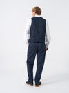 A model stands facing sideways against a neutral studio backdrop wearing the Navy Twill Field Waistcoat. The image displays the side profile, armhole shape, layered fit, deep navy twill material, and functional front pocket placement clearly.