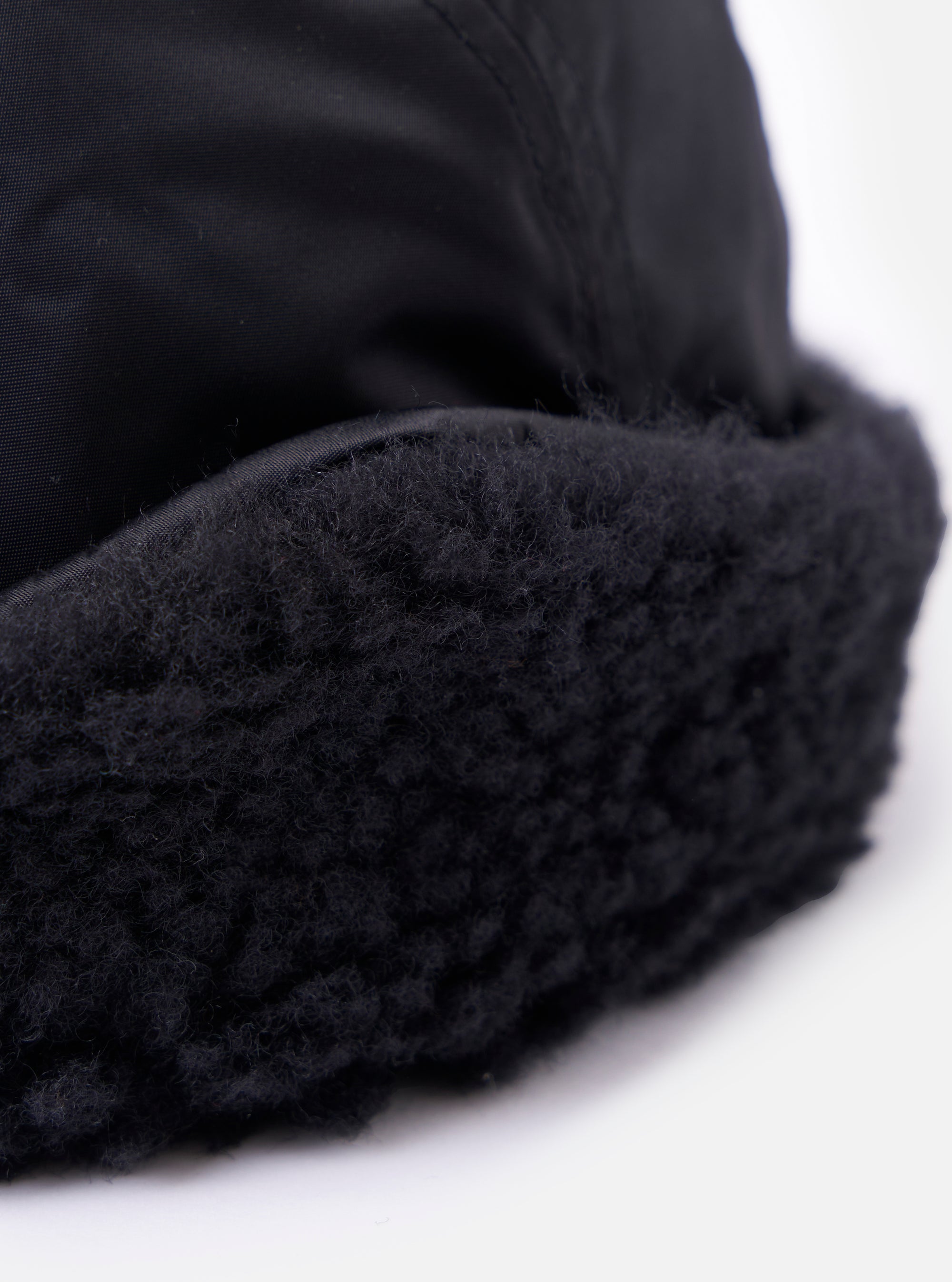 Close-up of the cableami® Black Military Nylon Twill Cap, showcasing the black nylon twill and plush black trim against a bright white background.