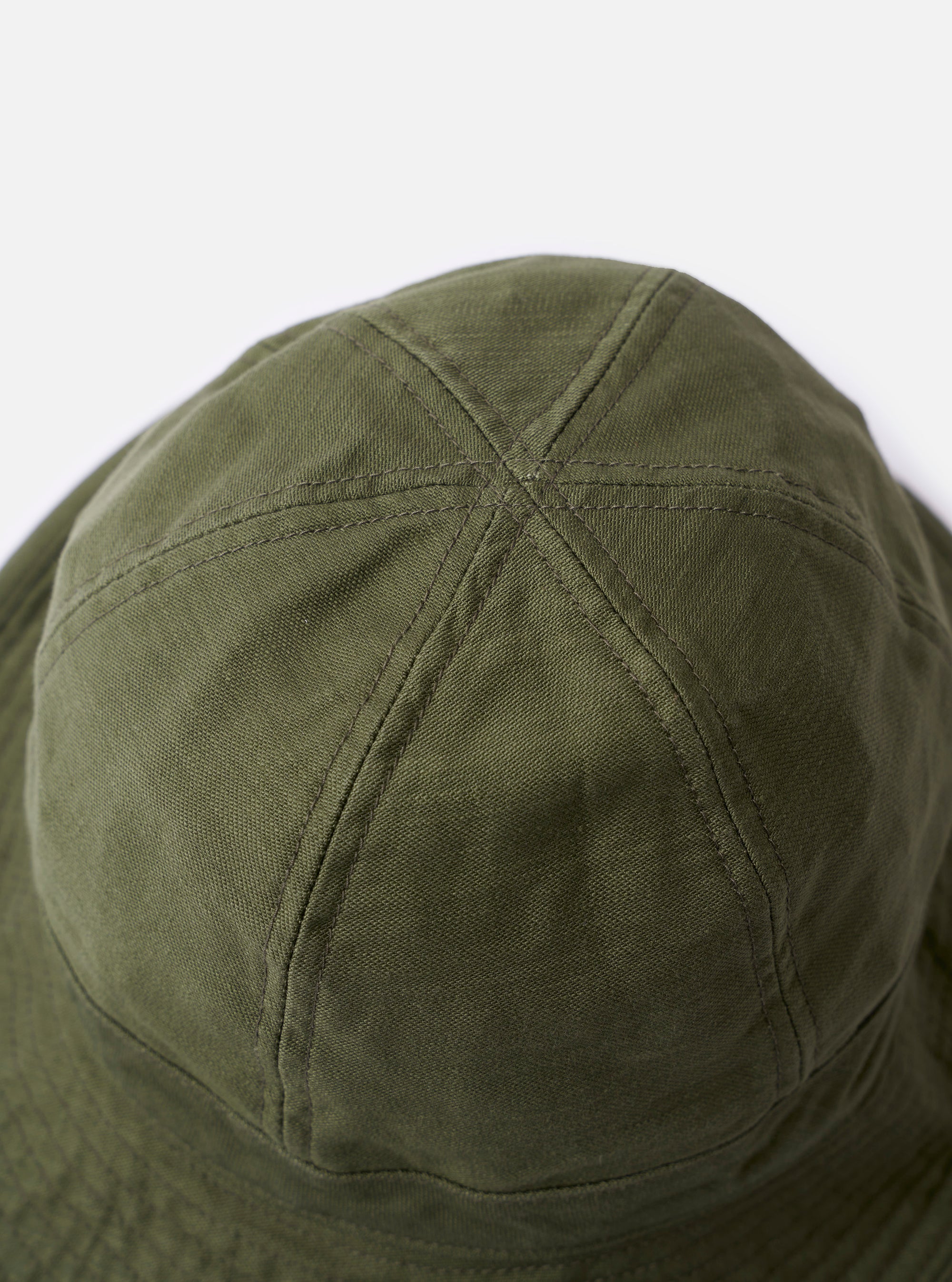 The cableami Dark Olive Baker Back Satin Cotton Metro Hat is shown from a side angle against a plain white background. The six-panel bucket hat features a downward-sloping brim, tonal topstitching, and a visible adjustable drawcord with a plastic toggle. The fabric has a matte, slightly textured back-satin finish in a dark olive green.
