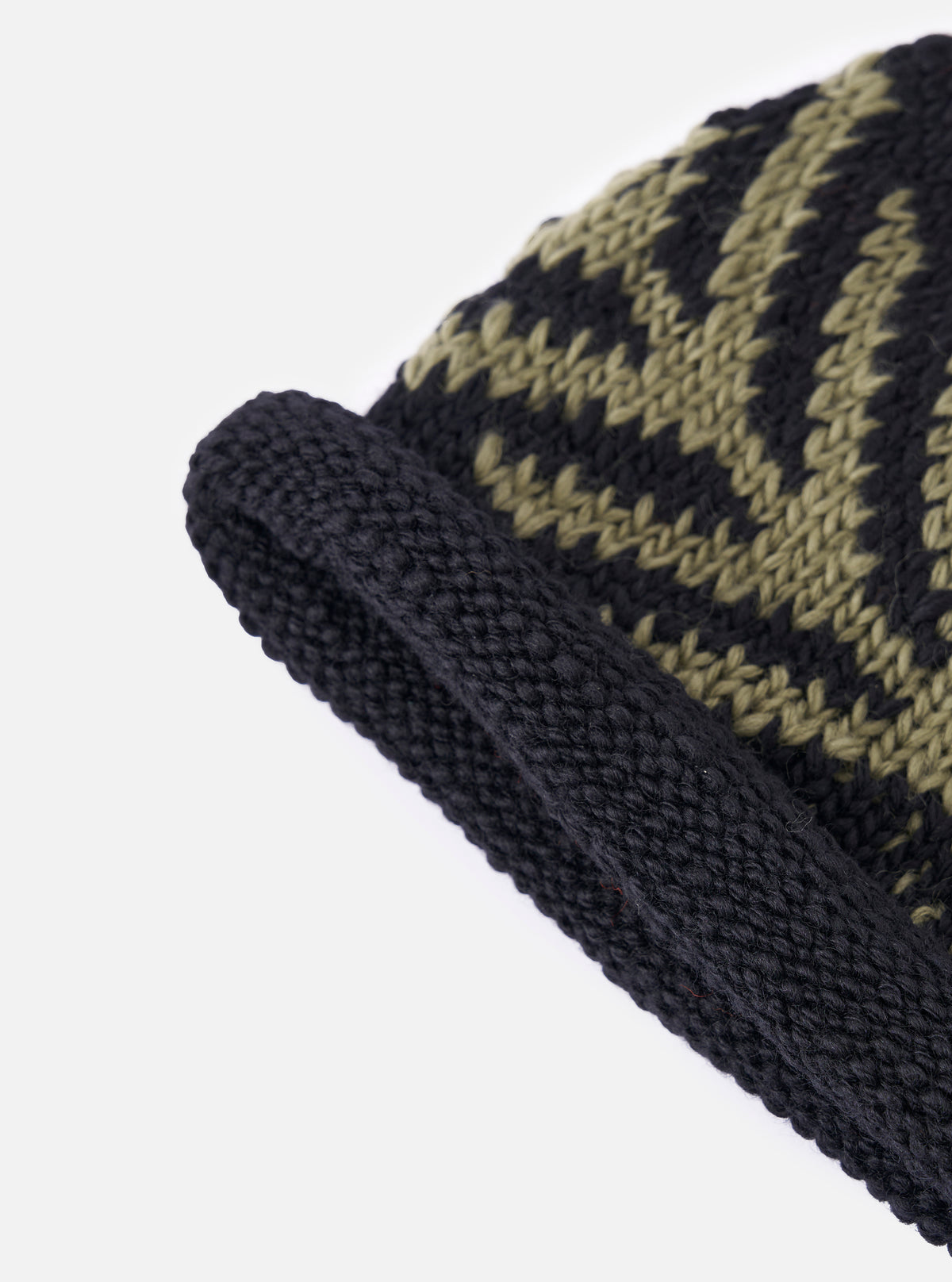 A close up image of the cableami® Black Wool Jacquard Watch Cap on a white background. Only half of the hat is displayed, emphasising the fine detail of the knit and its green arrow pattern.