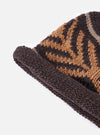 A close up image of the cableami® Brown Wool Jacquard Watch Cap on a white background. Only half of the hat is displayed, emphasising the fine detail of the knit and its orange arrow pattern.