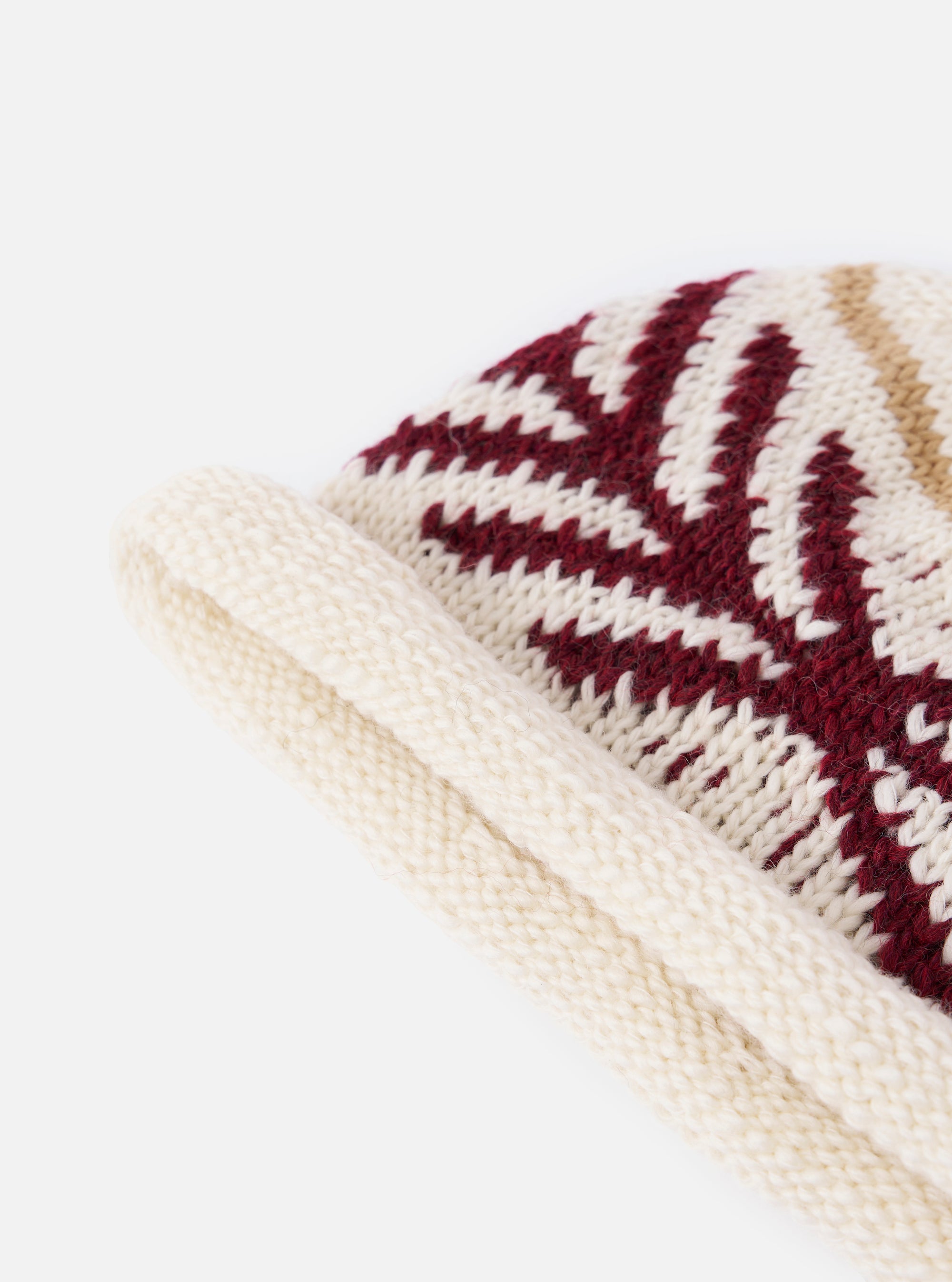 Close-up of the cableami® Ecru Wool Jacquard Watch Cap on a white background. The cap is ecru with a red and tan geometric pattern.