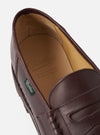 Close-up of a Paraboot Reims Marche loafer in cafe brown smooth leather, shot on a plain light grey backdrop. The penny strap and tassels are visible on the vamp. The tan leather insole shows the embossed Paraboot script logo with "Cousu Norvégien, Made in France" text. A green branded label is visible on the side welt.