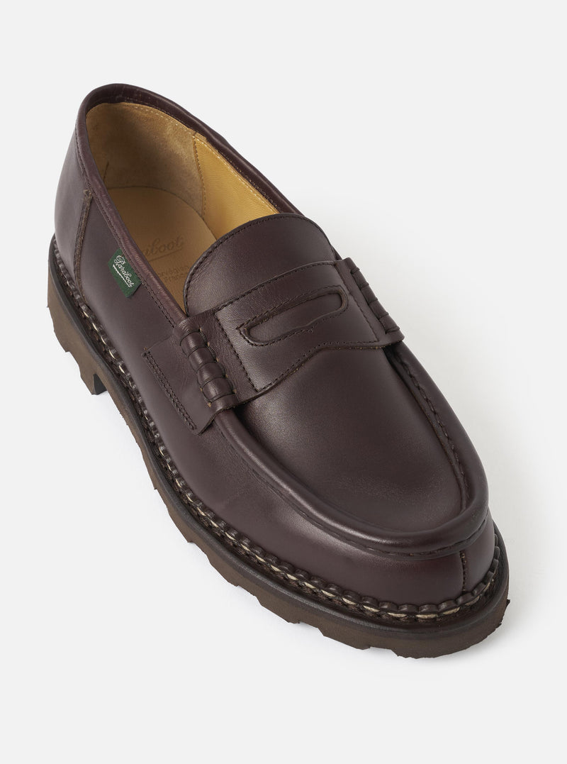 Side angle view of the Paraboot Cafe Leather Reims Marche loafer set against a plain light background. The image highlights the smooth dark brown leather upper, classic penny strap detail, stitched apron toe, and heavy-duty lugged rubber sole.