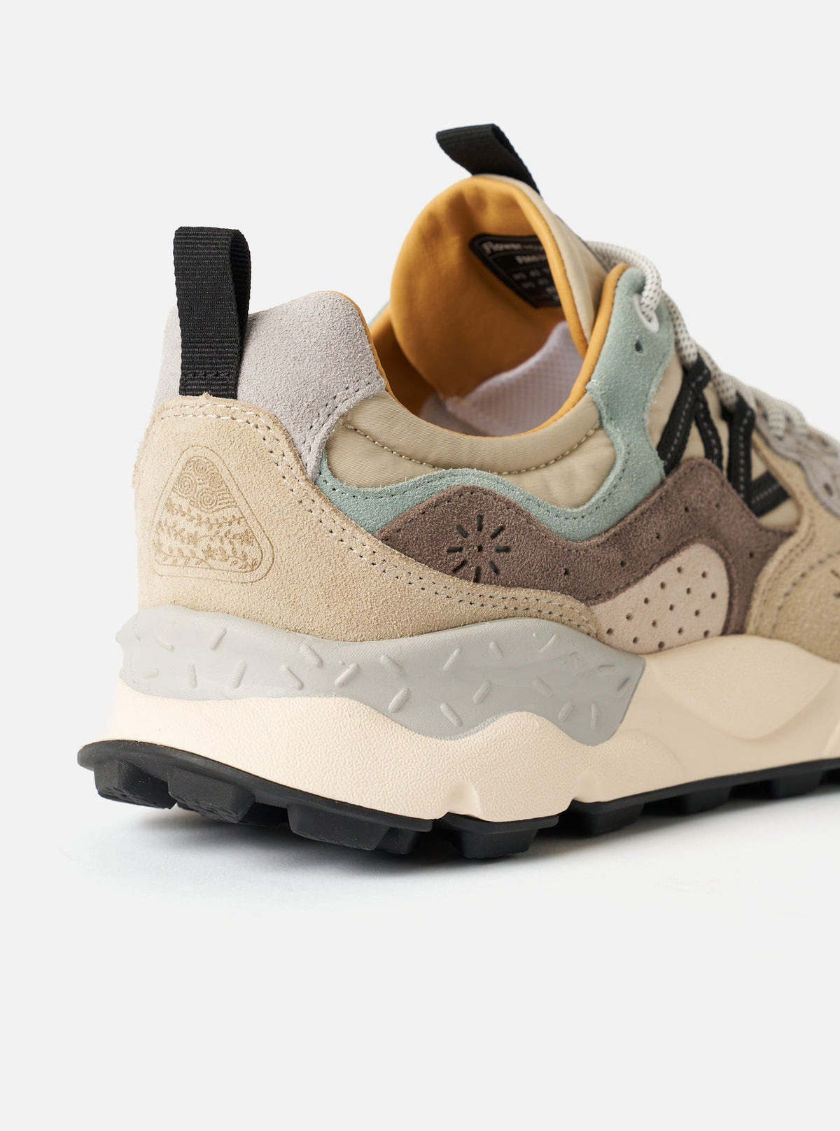 Back heel detail shot of the Flower Mountain Sand/Beige/Taupe Cow Velour Yamano 3 Uni sneaker against a plain light background. Features a leather pull tab, reinforced velour heel cup, layered taupe panels, and thick rubber outsole edge.