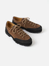 Pair of Paraboot Vel Marron suede lace-up shoes on a light grey studio backdrop. The uppers are tan-brown suede with a textured dark grey suede toe cap and heel panel. A dark brown leather collar trim lines the ankle. Five eyelets with bronze hardware lace up with a thick cord lace. The chunky black lug sole is prominently visible.