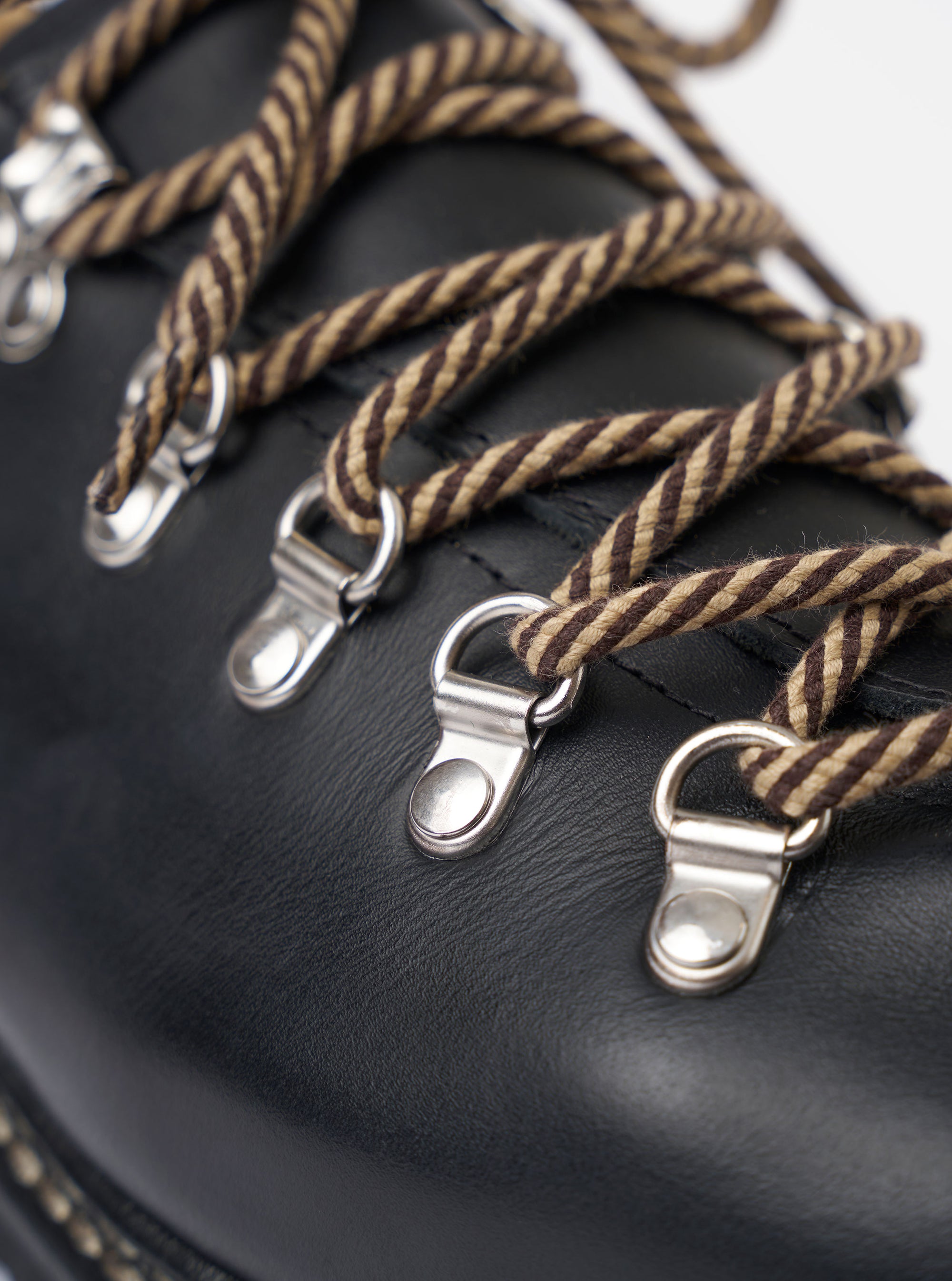 The Paraboot Black Leather Clusaz Jannu is shown as a studio shot against a plain white background. The low-top hiking-style shoe is crafted from smooth black leather and features a prominent Norwegian welt with visible stitching connecting the upper to the thick rubber lug sole. The design includes a rounded toe, D-ring metal eyelets with rope laces, and a wrap-over tongue construction.