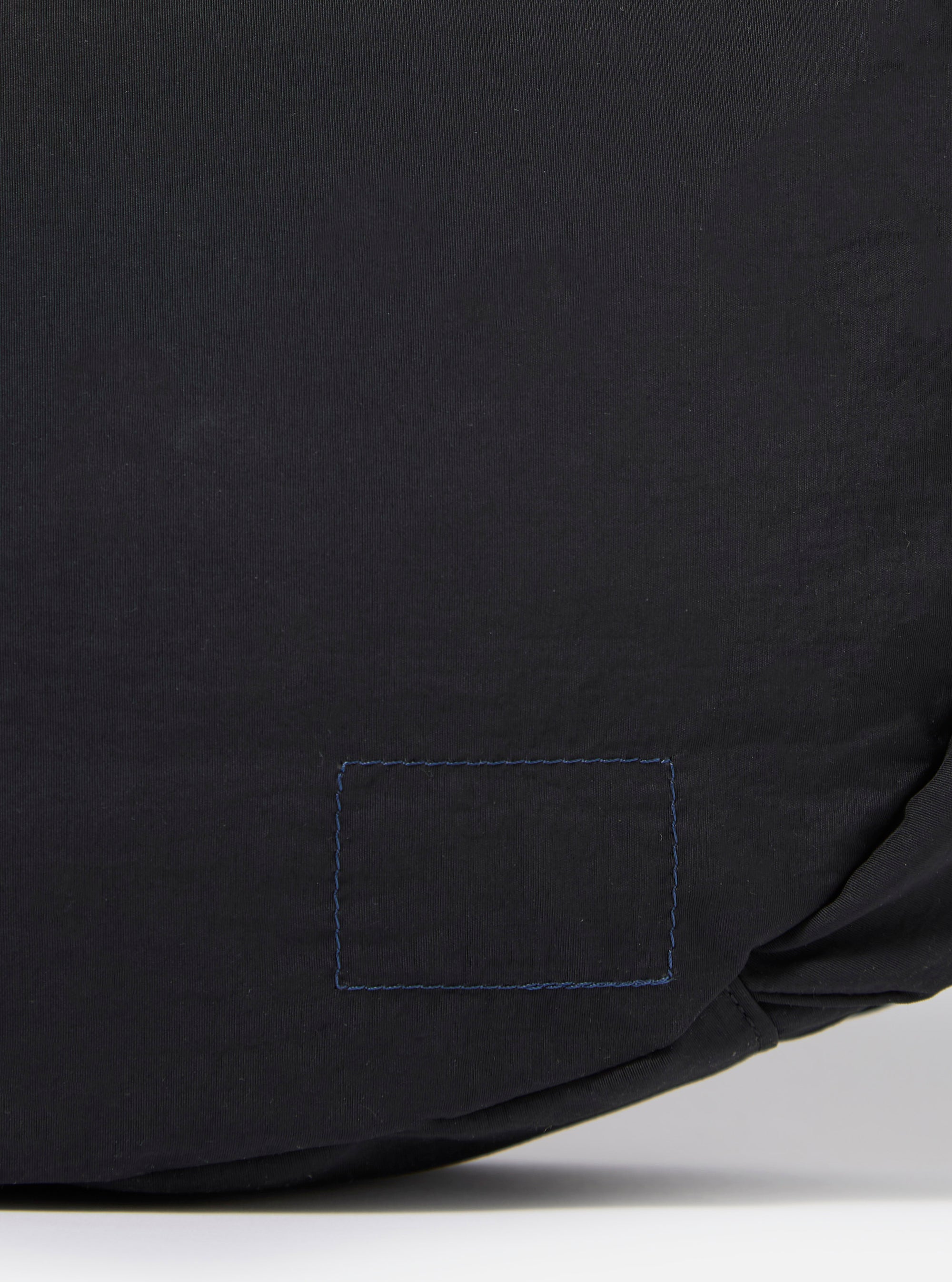 The master-piece x Universal Works Black Medium Canvas Shoulder Bag is shown from the back as a flat lay against a plain white background. The image highlights the clean construction of the black canvas bag, featuring a central vertical seam and the adjustable shoulder strap extending from the top corners.