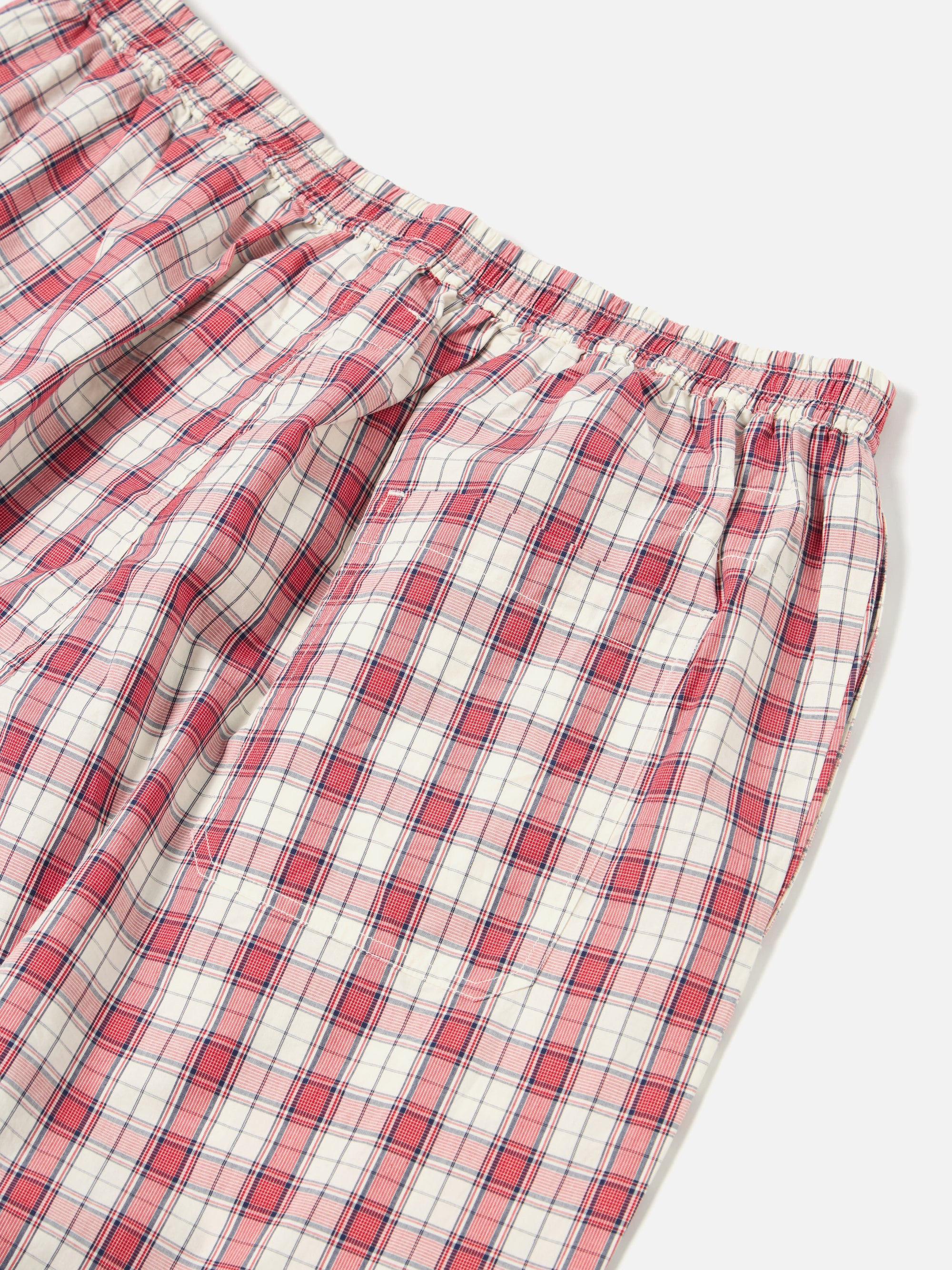 Close-up of the Red Cotton Check Pyjama Pant on a white surface. The red and white checkered pattern is visible, showcasing the soft cotton material and comfortable fit.