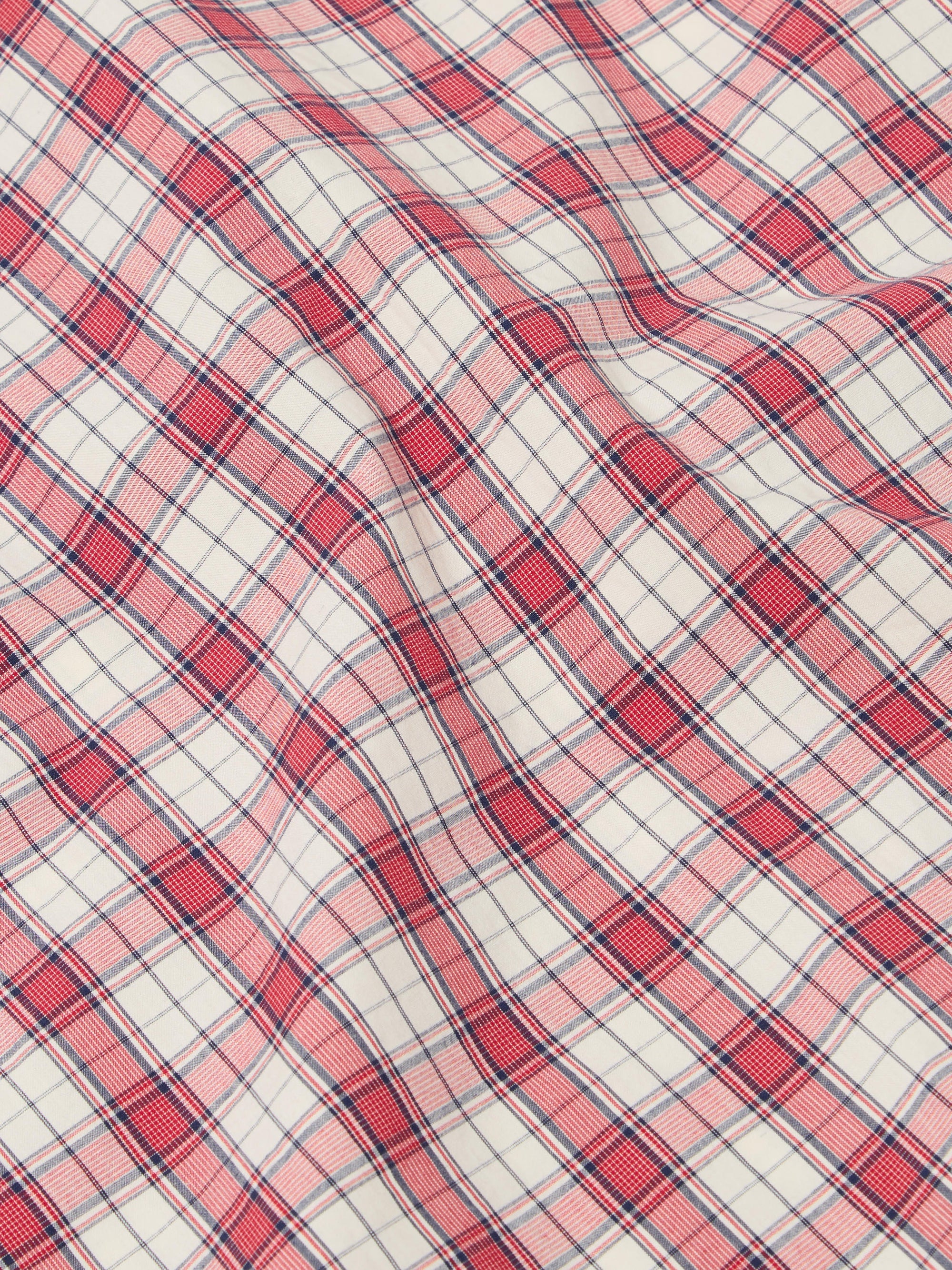 Close-up of the Red Cotton Check Pyjama Pant fabric. The red and blue plaid cotton is softly draped on a flat surface.