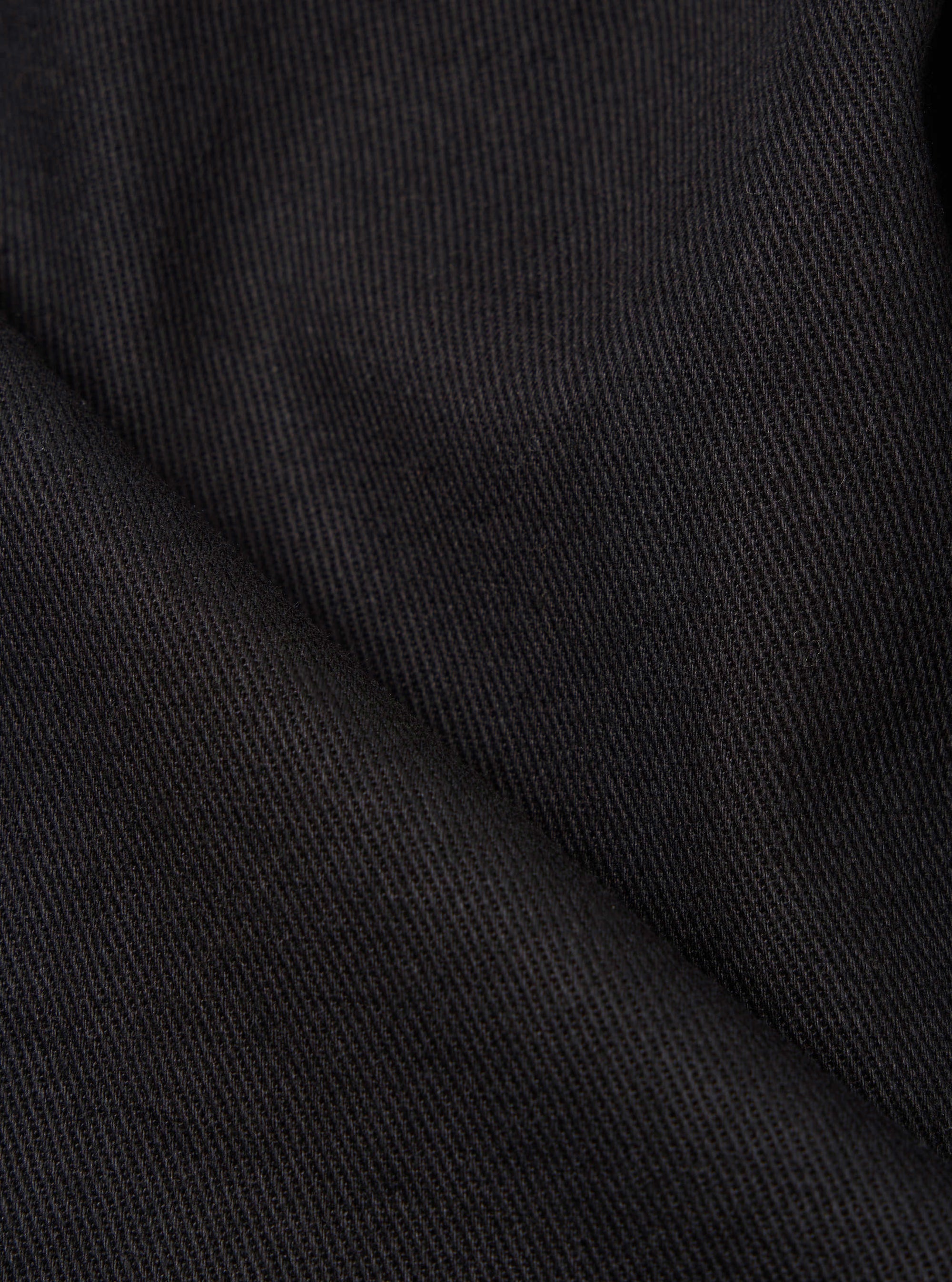 Close-up of the Black Twill Fatigue Pant (Undarted), showcasing the fabric's texture and dark color. The image is tightly cropped, highlighting the twill weave against a plain background.