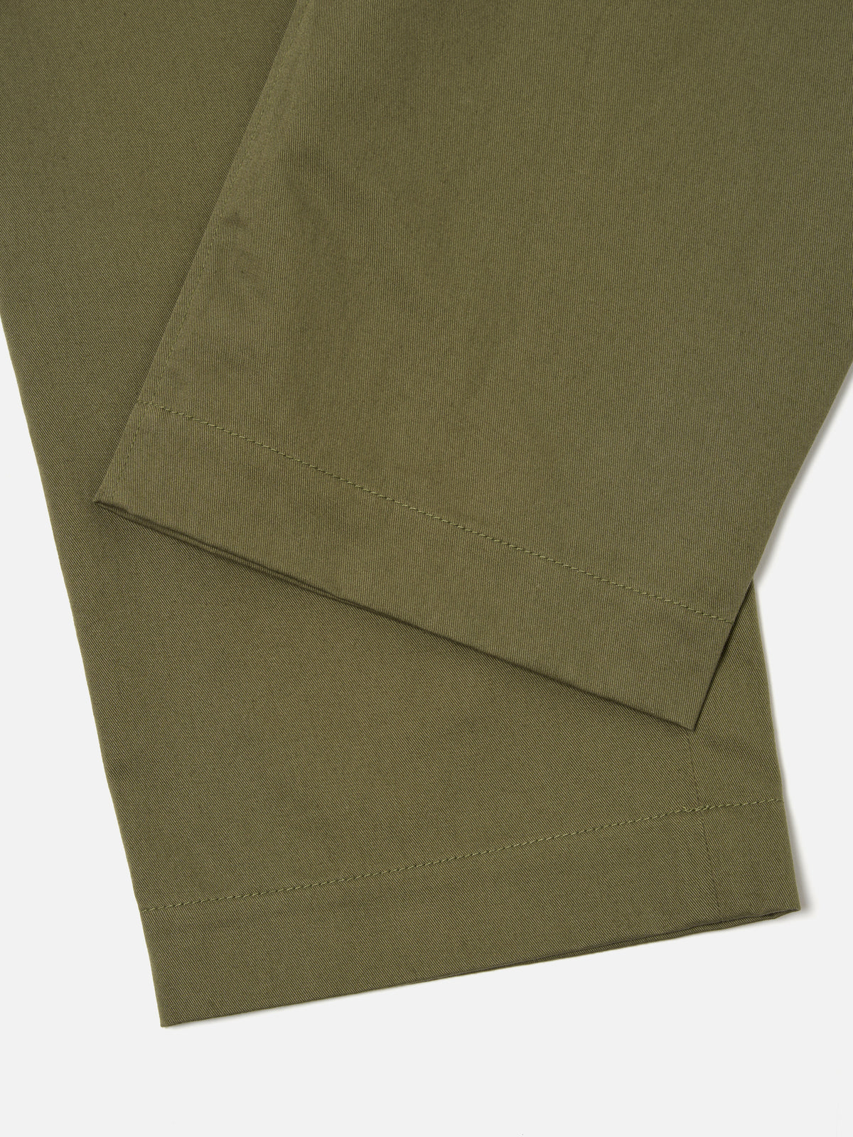 Close-up of the light olive Twill Duke Pant on a white surface. The twill fabric is visible, showcasing the texture and color of the pants.