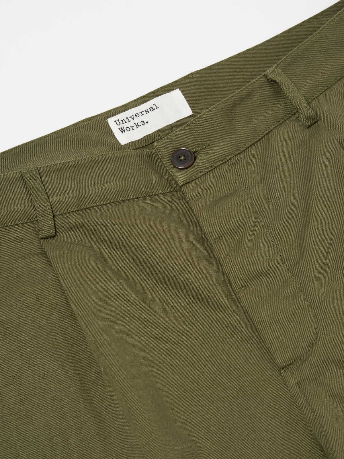 Close-up of the Light Olive Twill Duke Pant on a white background. The twill fabric is visible, showcasing the texture and color. The button and waistband details are also in focus.