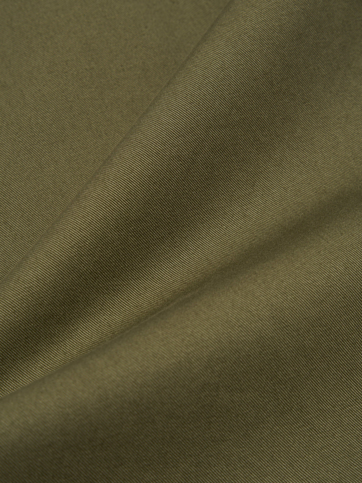 Close-up of the Light Olive Twill Duke Pant fabric. The twill weave is visible, showing the texture and color of the material. The fabric is draped to highlight its quality.