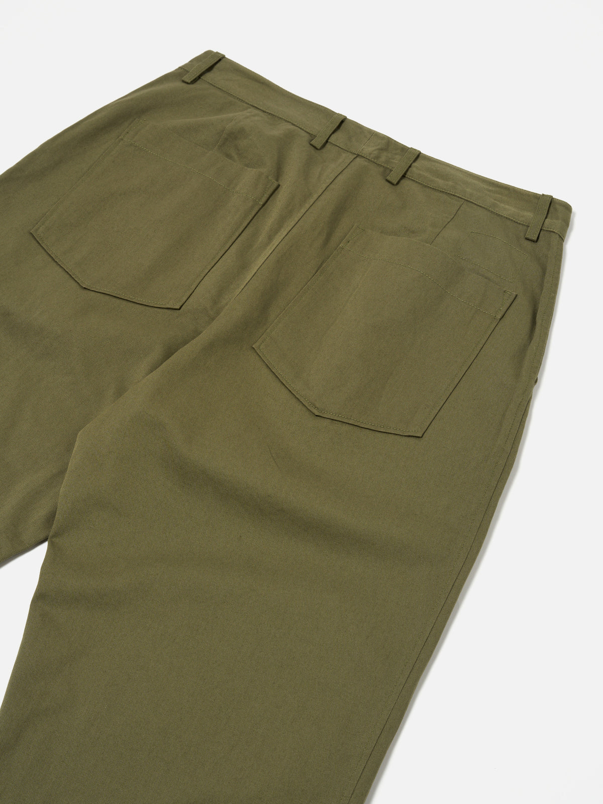 Close-up of the back of light olive twill Duke Pant on a white surface. The pants have a relaxed fit and visible back pockets.