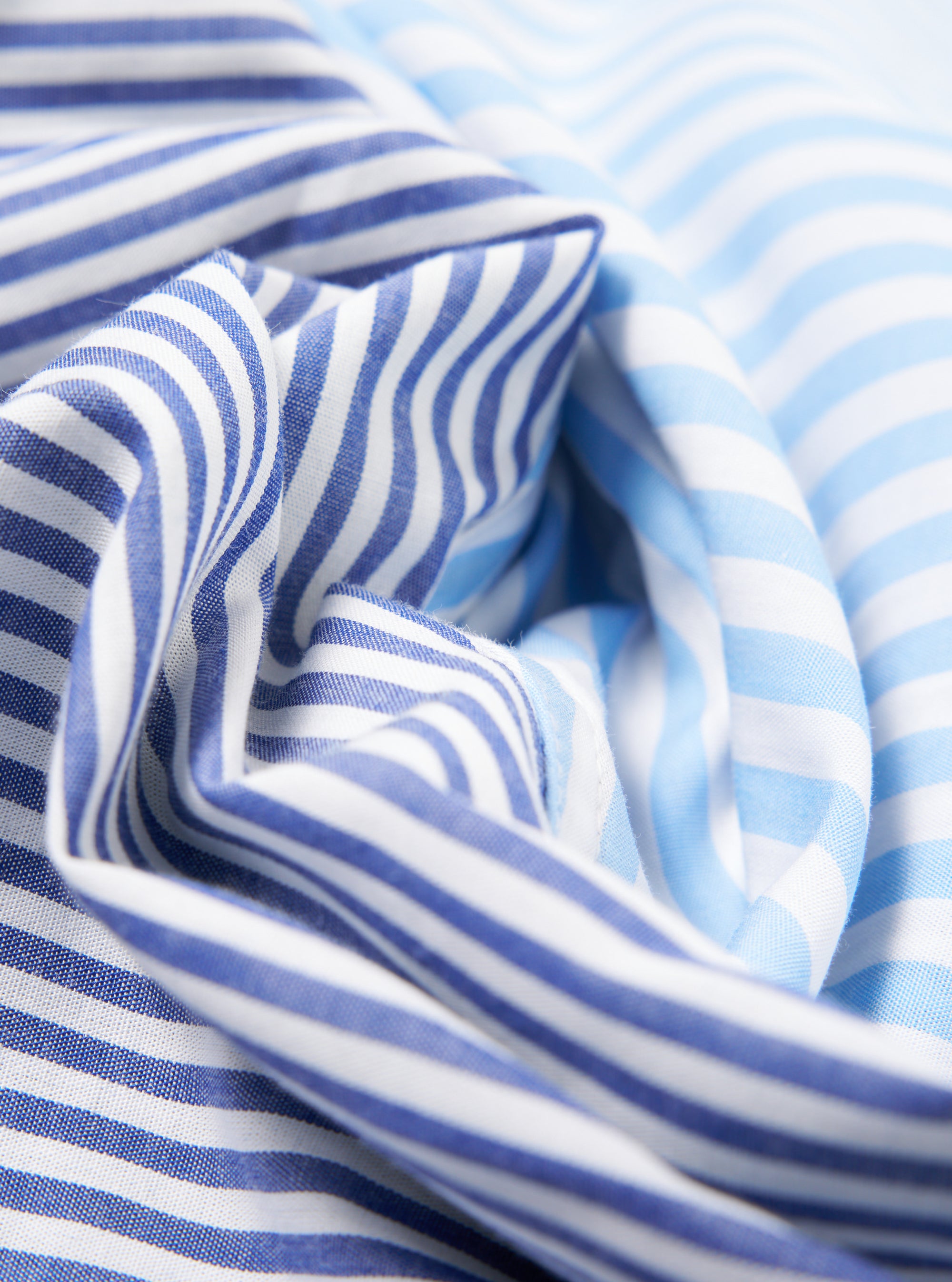 Close-up of the Blue Classic Mix Boxer Short fabric. Features blue and white stripes in a soft cotton blend. The material is artfully draped to showcase its texture.