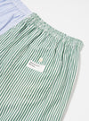 Close-up of the Blue Classic Mix Boxer Short on a white surface. Features green and white stripes, a pocket with a button, and the Universal Works logo.