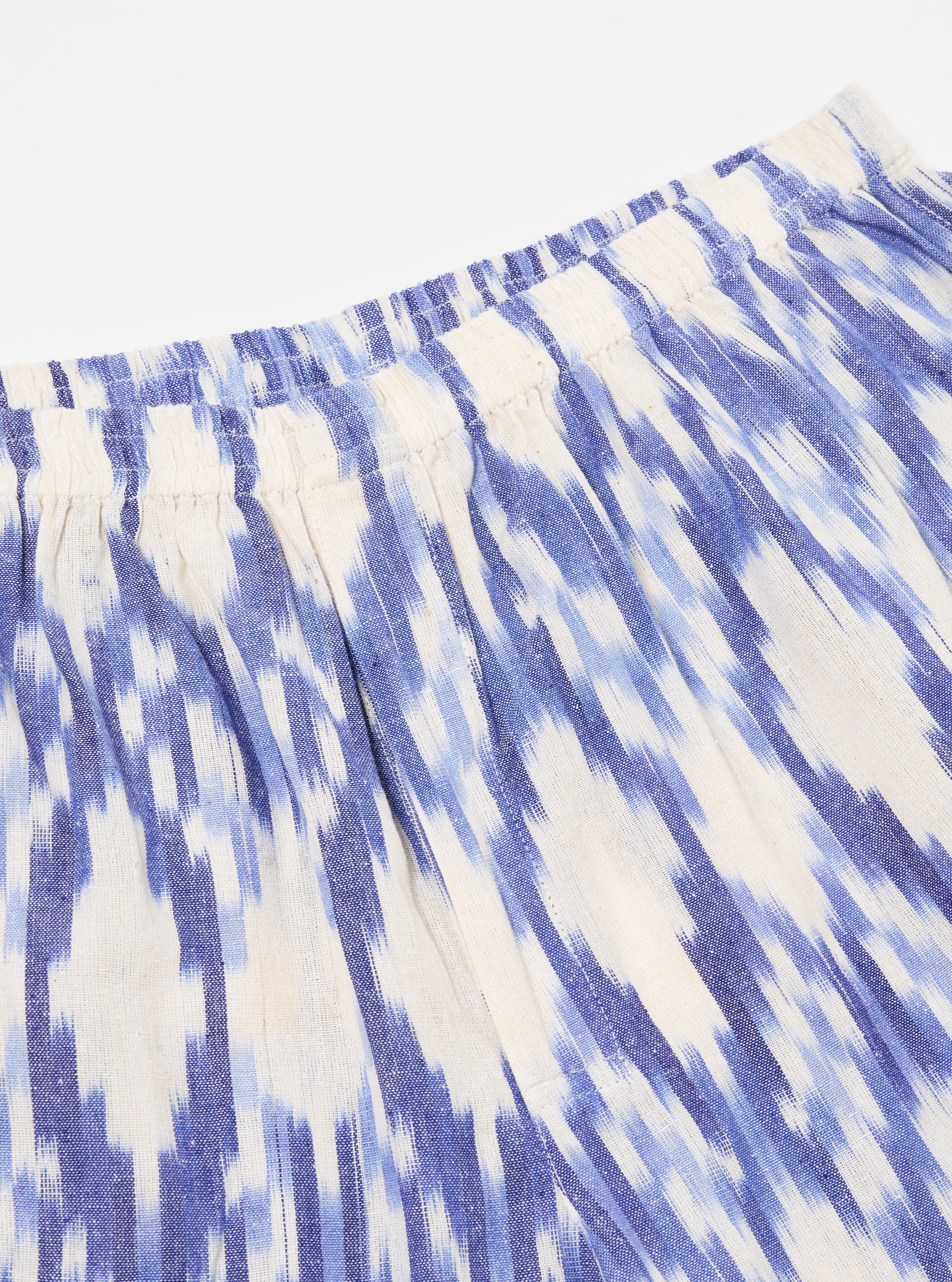 Close-up of the Ecru Ikat I Cotton Boxer Short. The cotton fabric features a blue ikat pattern on an ecru background. The shorts have an elastic waistband. Shot on white.