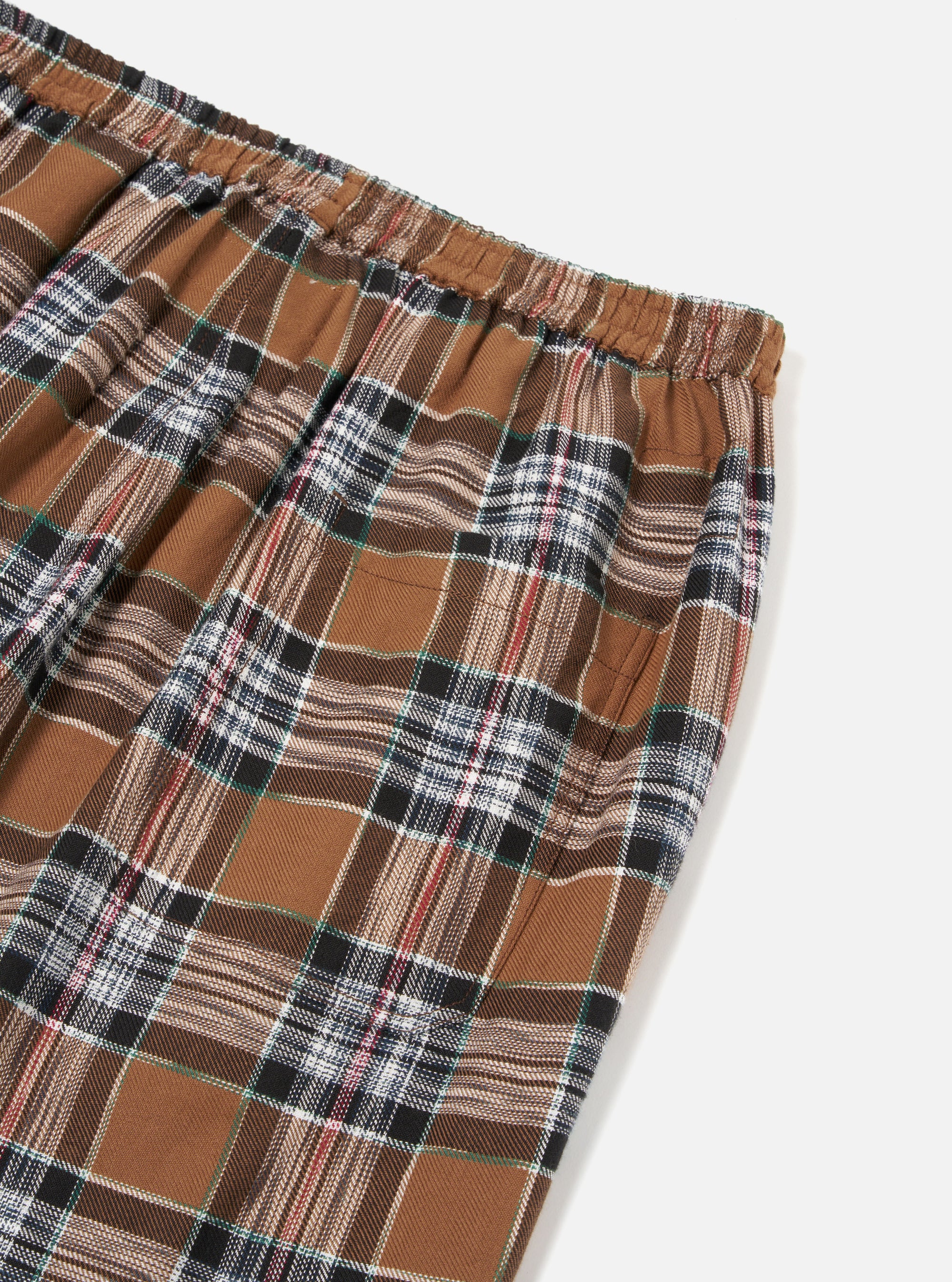 Close-up of the Brown Ikat Twill Check Long Pyjama Set. Brown, black, white and red check pattern. Elasticated waist. Shot on a white background.