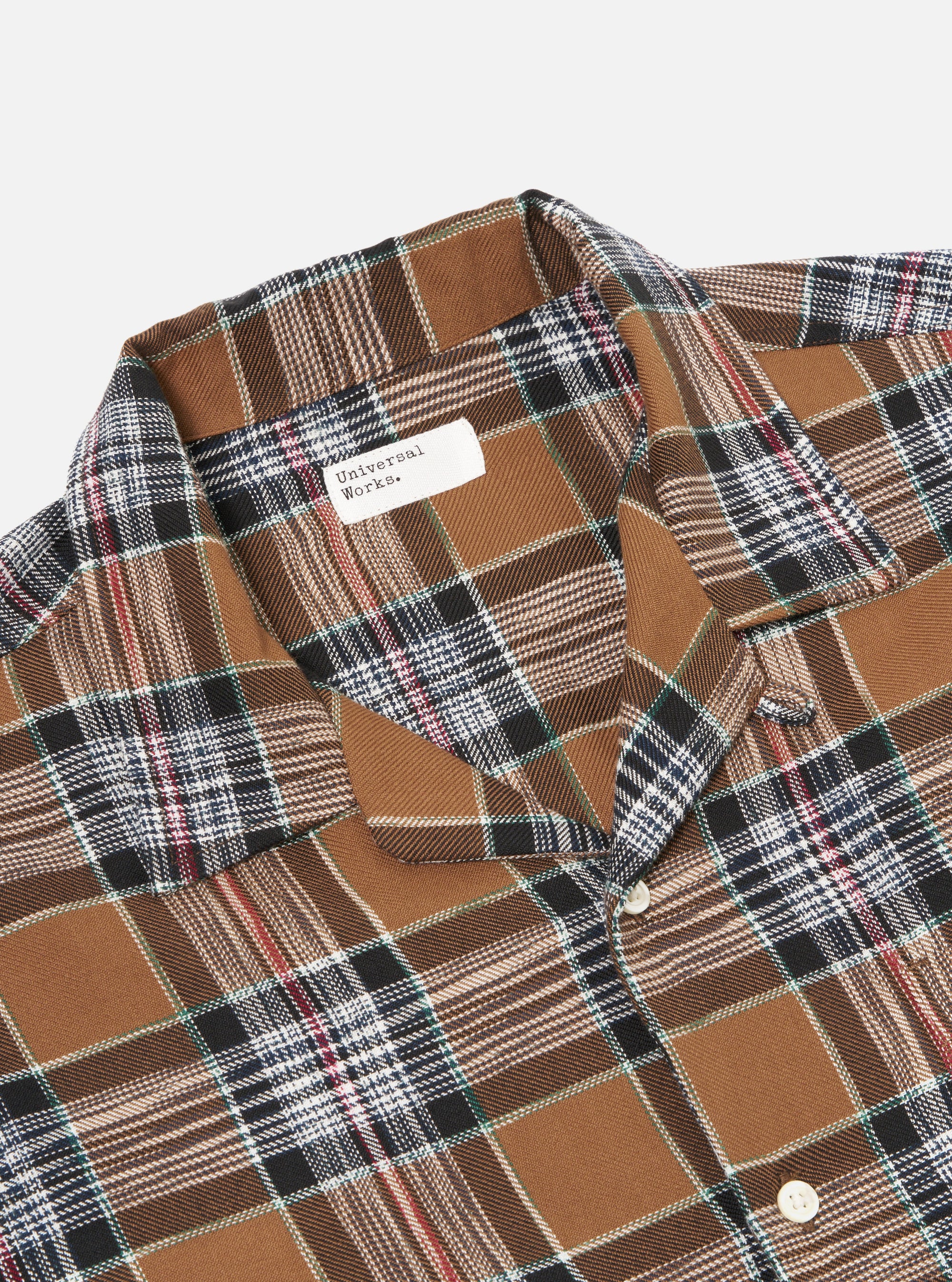 Close up of the Brown Ikat Twill Check Long Pyjama Set. The fabric is brown with a plaid pattern of black, white, red and green lines. The background is plain white.