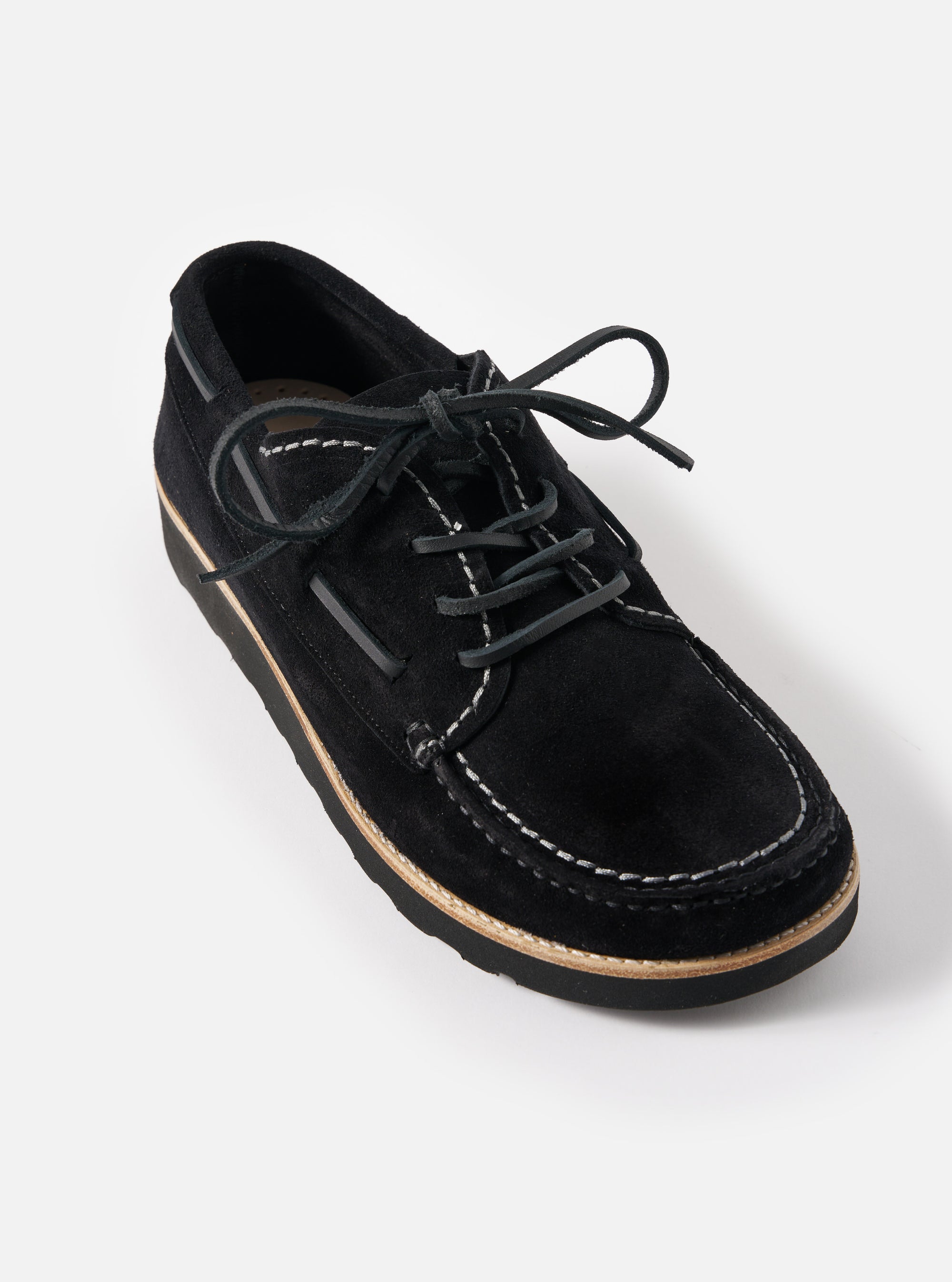 Studio shot of Zardus for Universal Works Black Suede Oliver shoe. The black suede lace-up shoe features contrast stitching and a light sole. Set against a white backdrop.