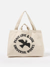 The Ecru Canvas Market Tote bag. The bag is ecru-colored canvas with black text and a bird graphic. The background is a plain white studio backdrop.